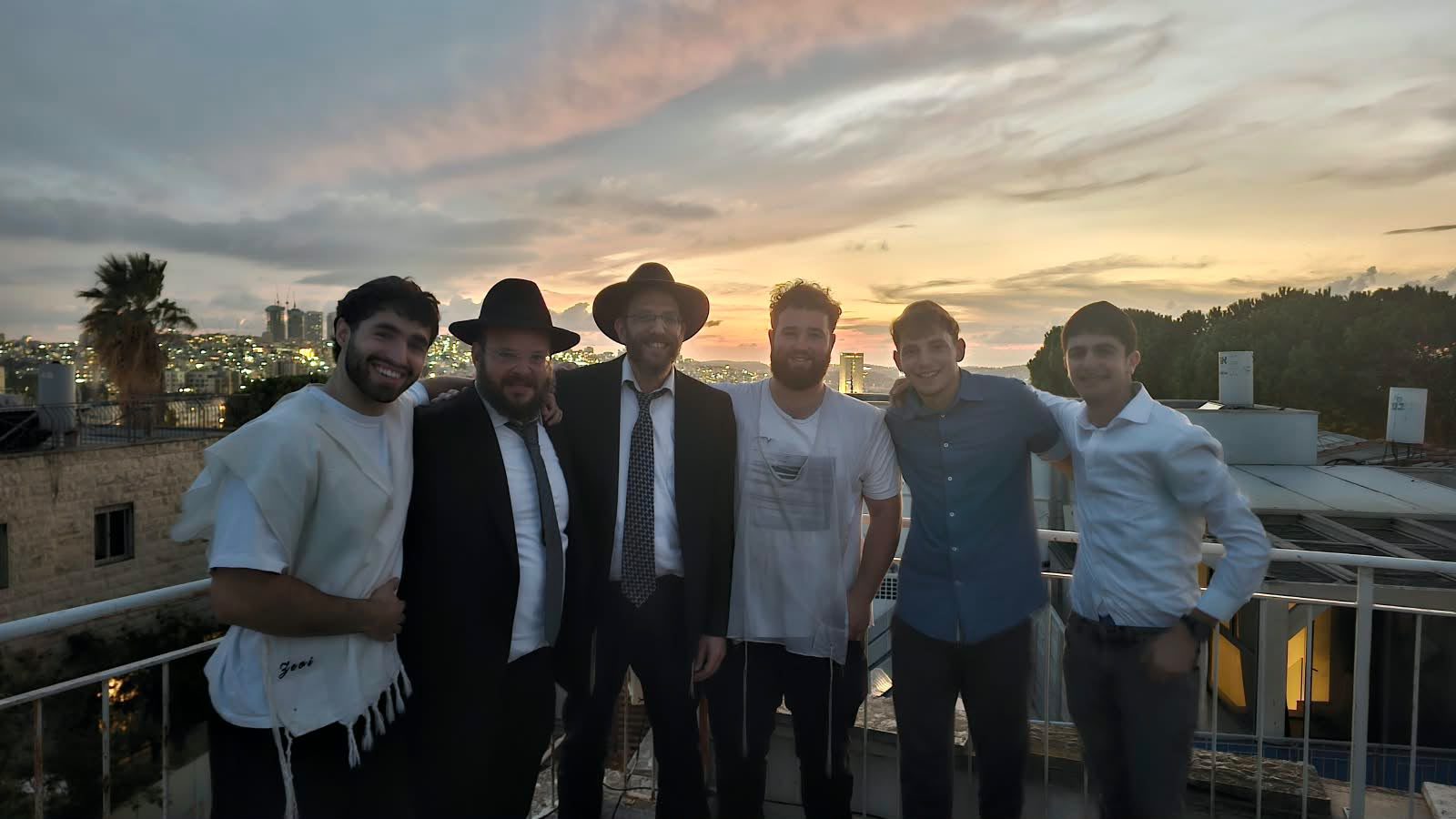 Talmidim and a Rebbi together on a rooftop at sunset